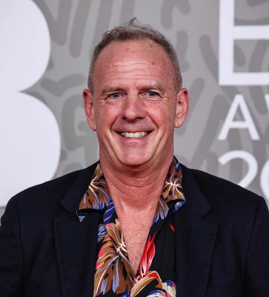 a man in a suit and hawaiian shirt smiles for the camera