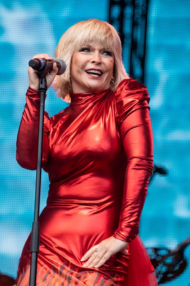 a woman in a red dress is singing into a microphone