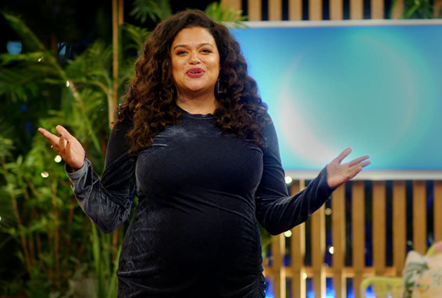 a woman in a black dress stands in front of a blue screen