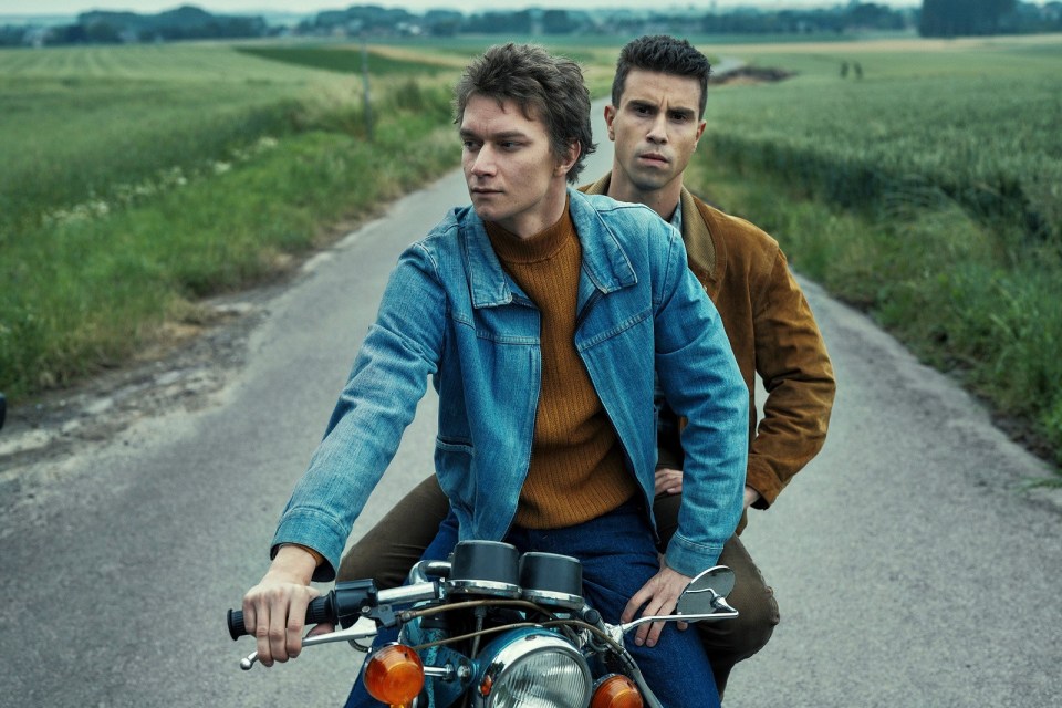 two men are riding a motorcycle down a road