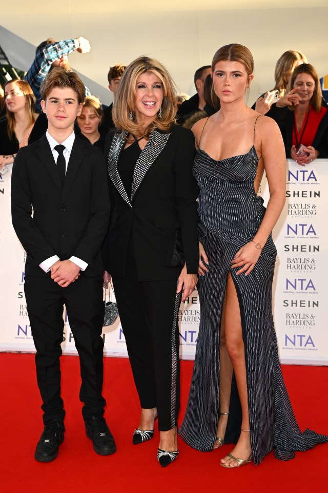 three people on a red carpet that says shein on it