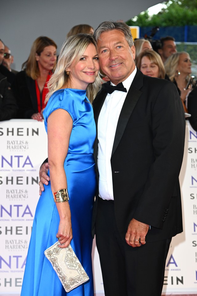 a man in a tuxedo and a woman in a blue dress pose for a photo on a red carpet that says shein
