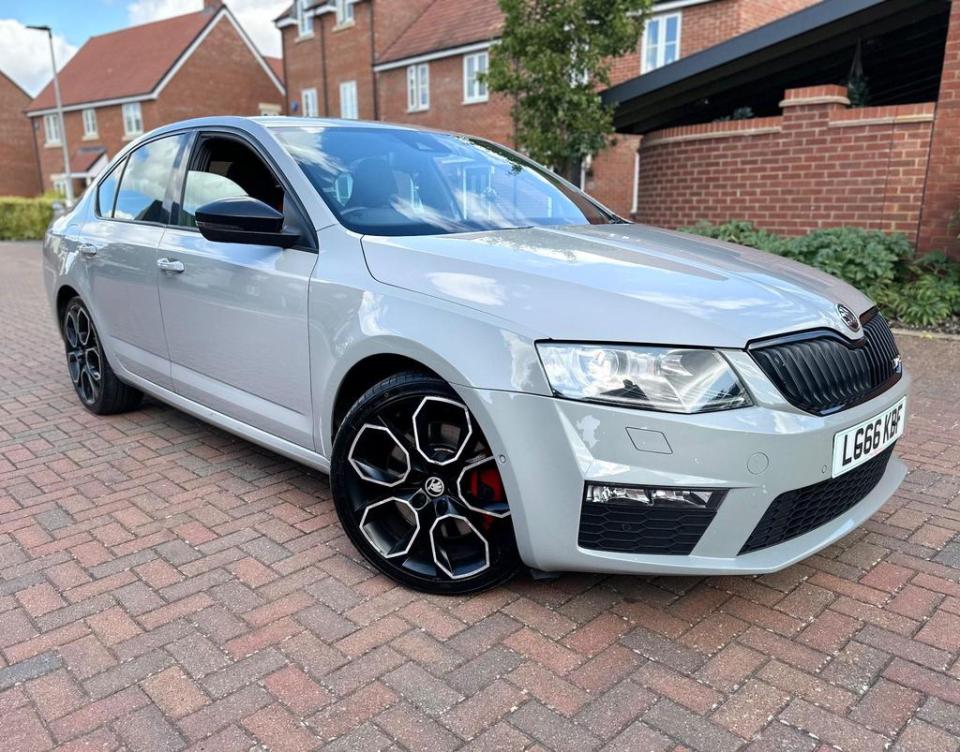 a silver skoda is parked on a brick driveway
