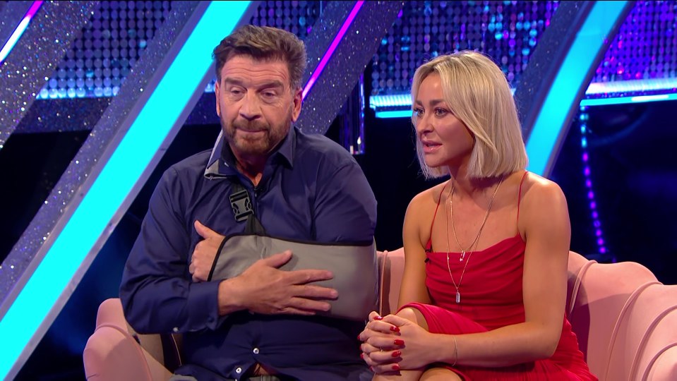 a man with a cast on his arm sits next to a woman in a red dress