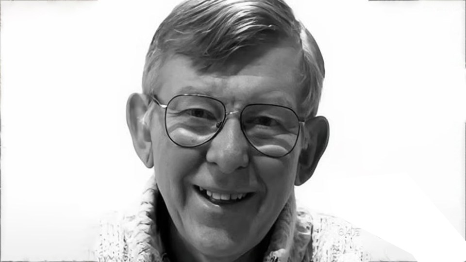 a man wearing glasses is smiling in a black and white photo