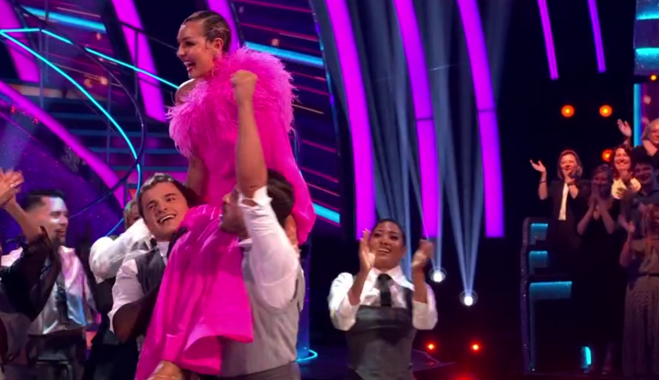 a man is carrying a woman in a pink dress on his shoulders