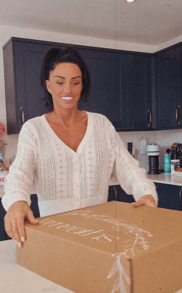 a woman in a white sweater is holding a cardboard box that says ' emma ' on it