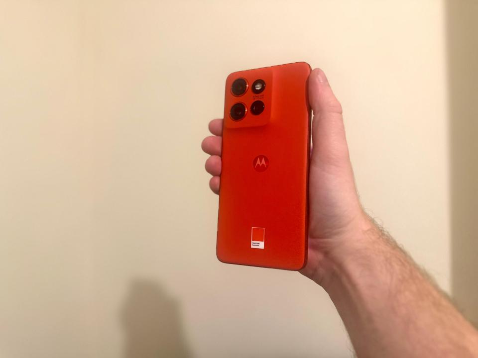 a person is holding a red motorola phone in their hand