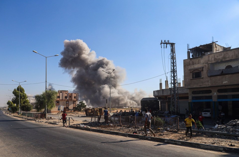 a man stands on the side of the road looking at smoke coming out of a building