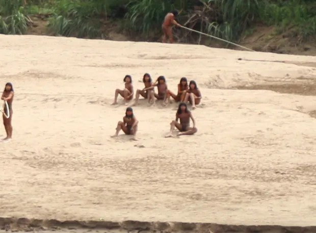 a group of people are sitting in the sand on a beach