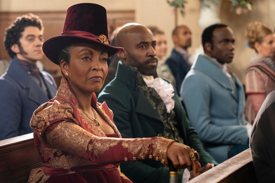 a woman in a top hat sits in a church with other people