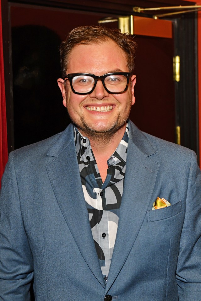 a man wearing glasses and a blue suit smiles for the camera