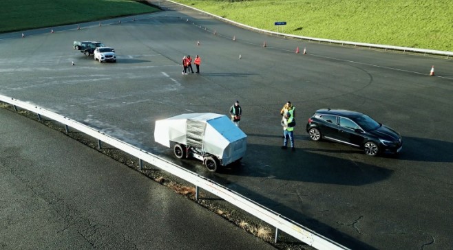 a black car is pulling a white trailer on a road