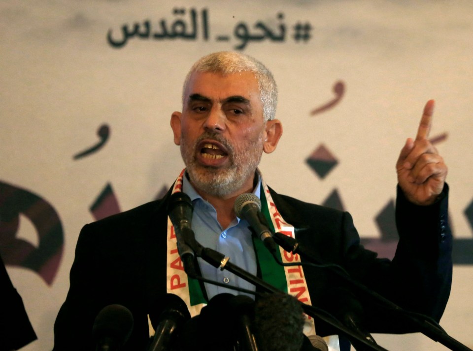 a man wearing a palestine scarf is speaking into a microphone