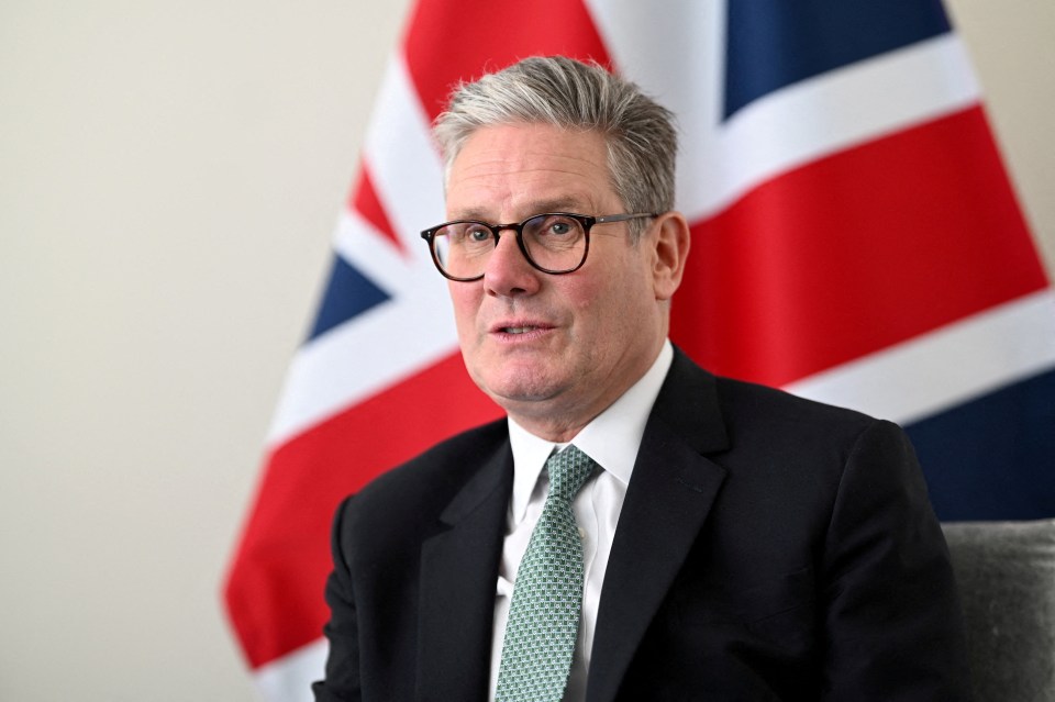 a man in a suit and tie stands in front of a flag