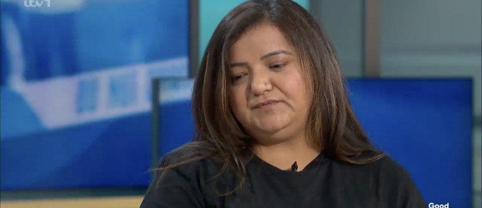 a woman in a black shirt is sitting in front of a television .