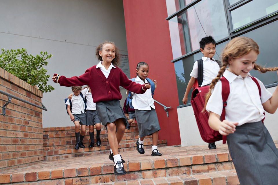 a group of children in school uniforms are walking down stairs