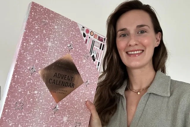 a woman holds up a pink advent calendar