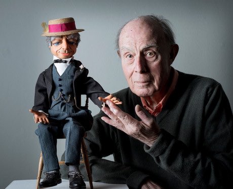 a man sitting next to a puppet wearing a hat