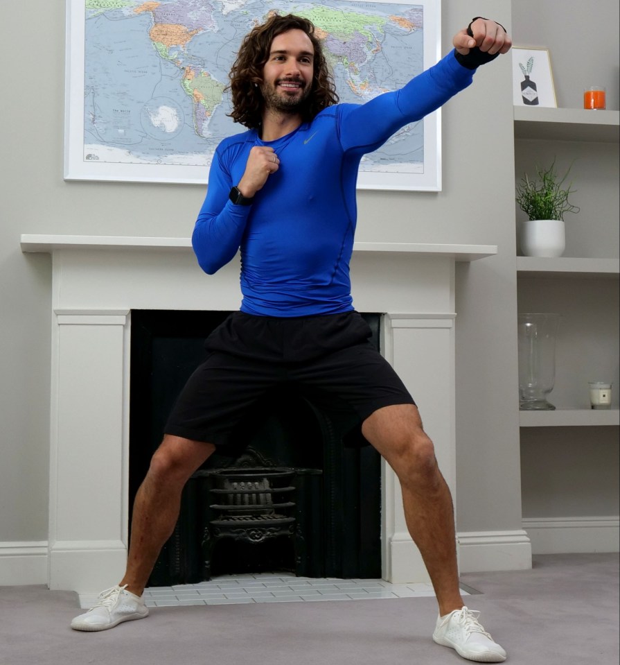 a man in a blue shirt is squatting in front of a fireplace