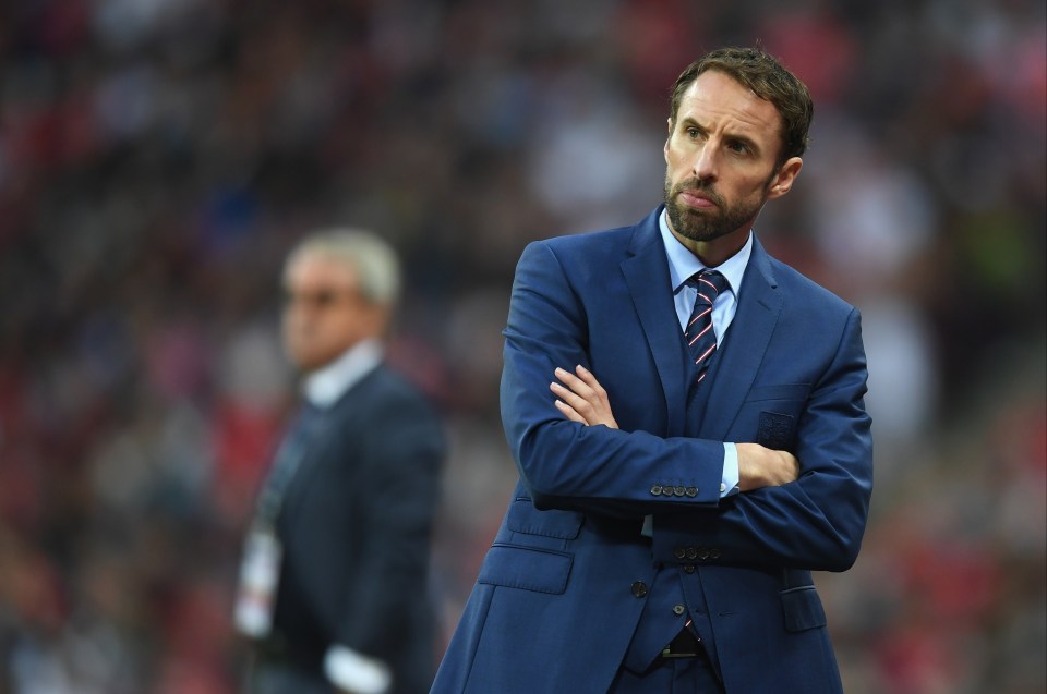 a man in a suit and tie stands with his arms crossed