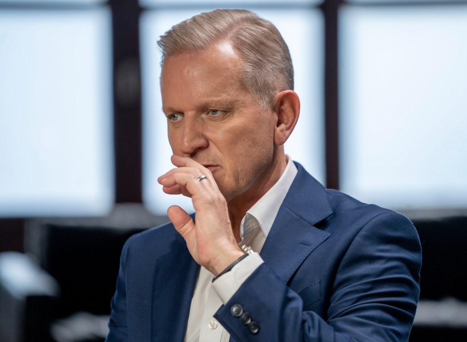 a man in a blue suit and white shirt is covering his mouth with his hand