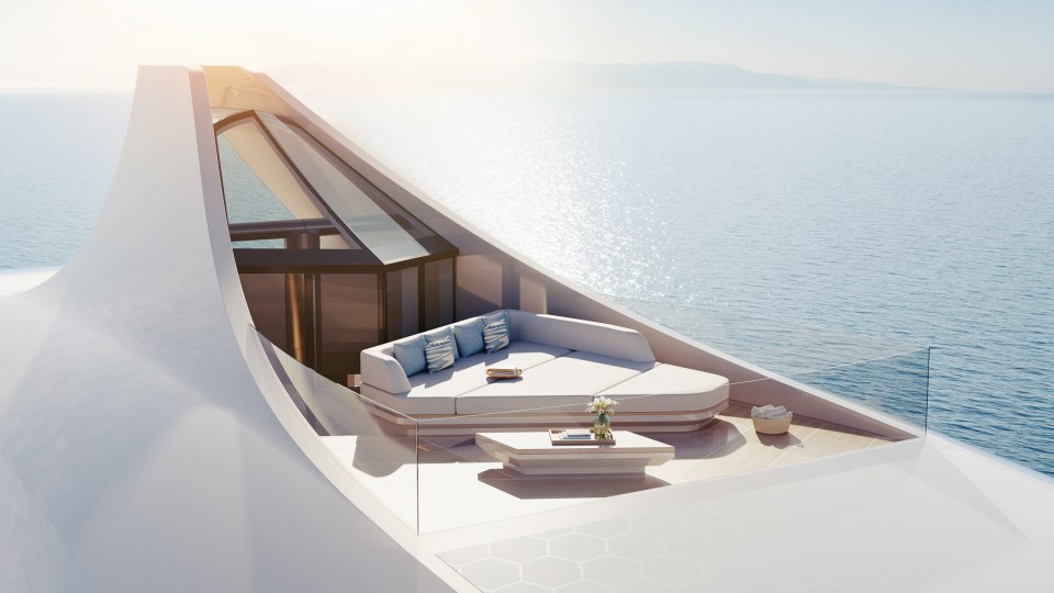a white couch sits on a balcony overlooking the ocean