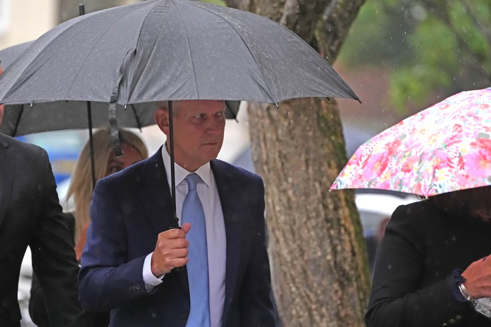 a man in a suit and tie holding an umbrella in the rain