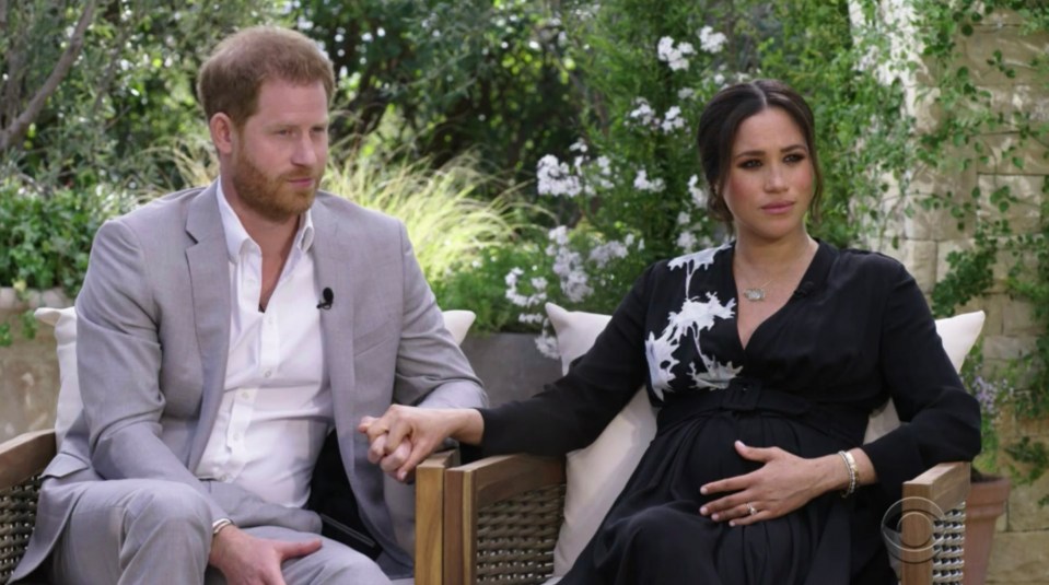 a man in a suit sits next to a pregnant woman in a black dress