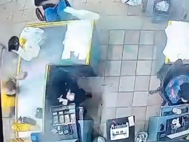 a group of people are standing around a counter in a restaurant .