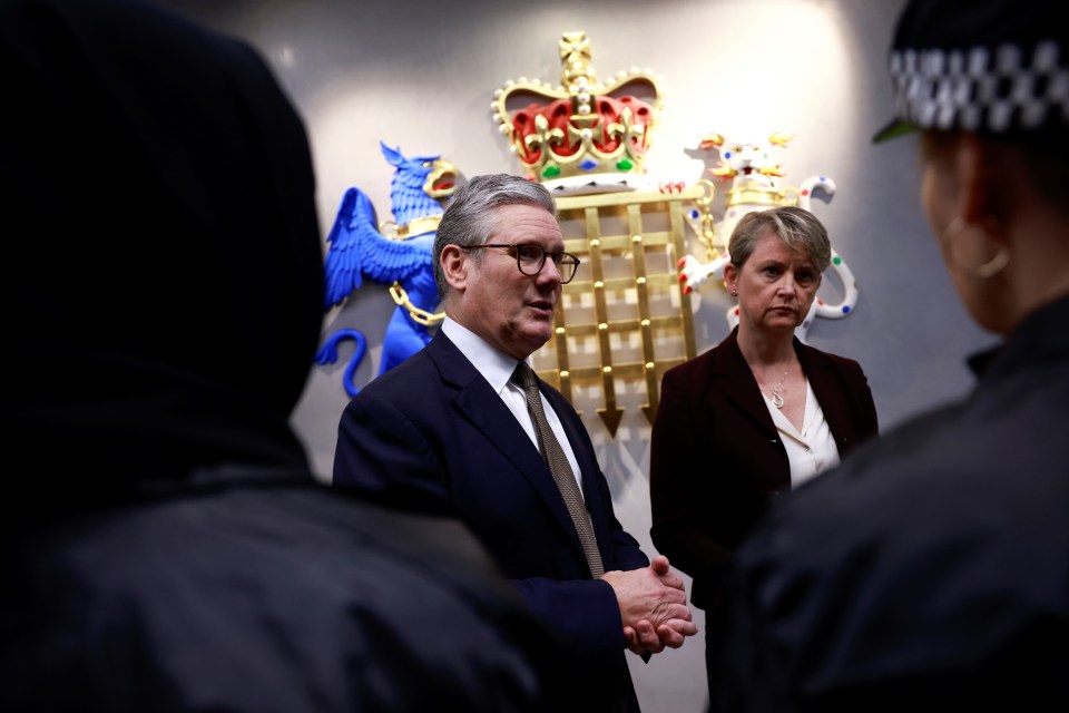 a man and a woman are standing in front of a coat of arms