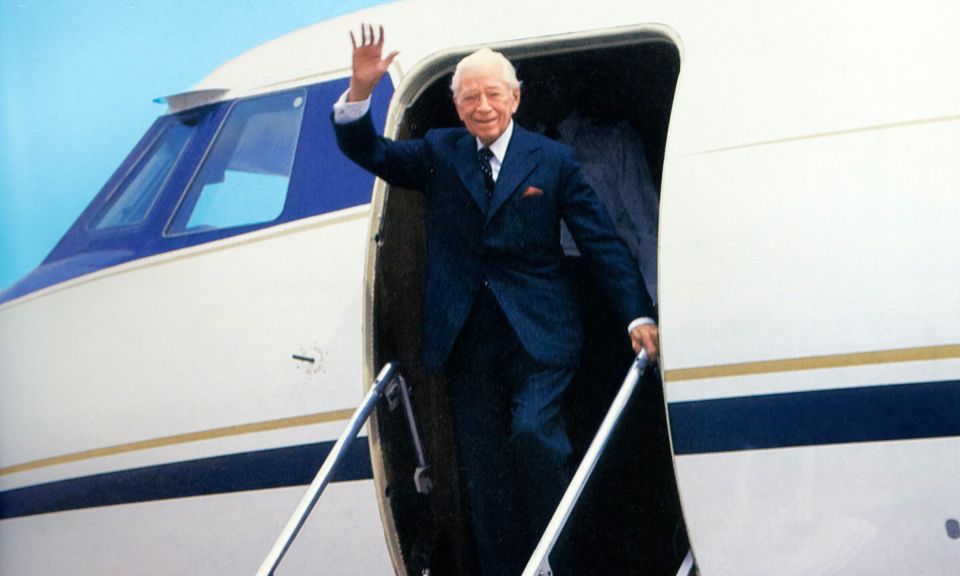 a man in a suit is waving from the door of an airplane