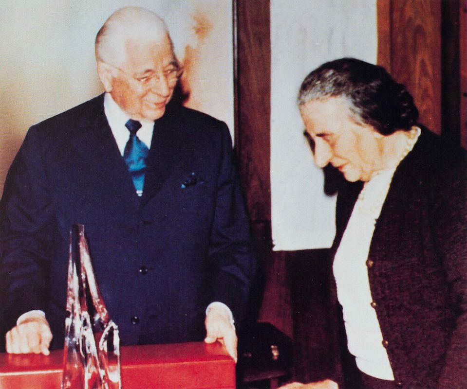a man in a suit and tie stands next to a woman in a black jacket