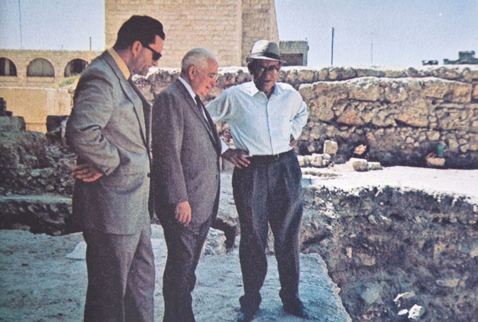 three men are standing in front of a stone wall