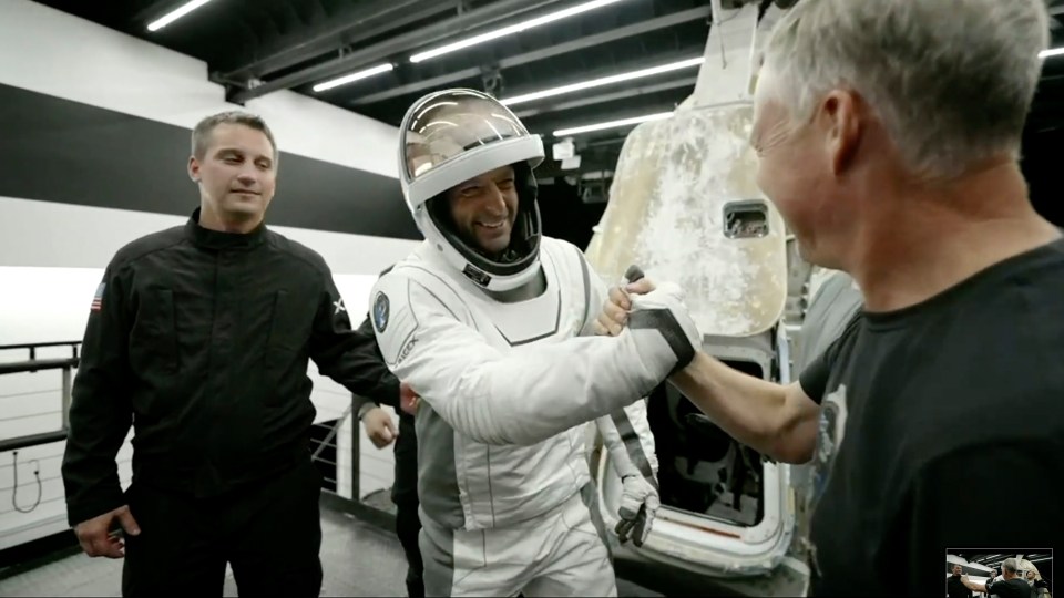a man in a space suit is shaking hands with another man