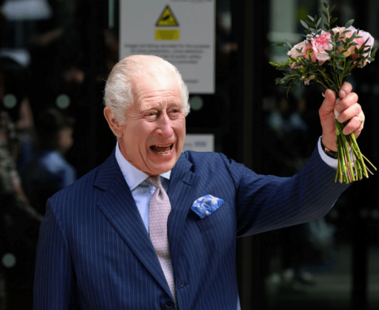 a man in a suit holds up a bouquet of pink flowers