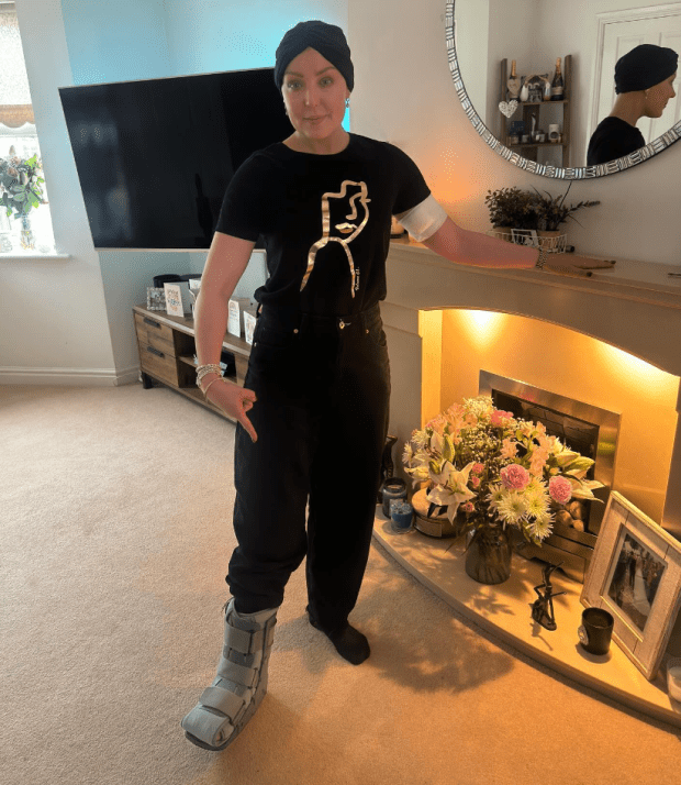 a woman standing in front of a fireplace wearing a black shirt