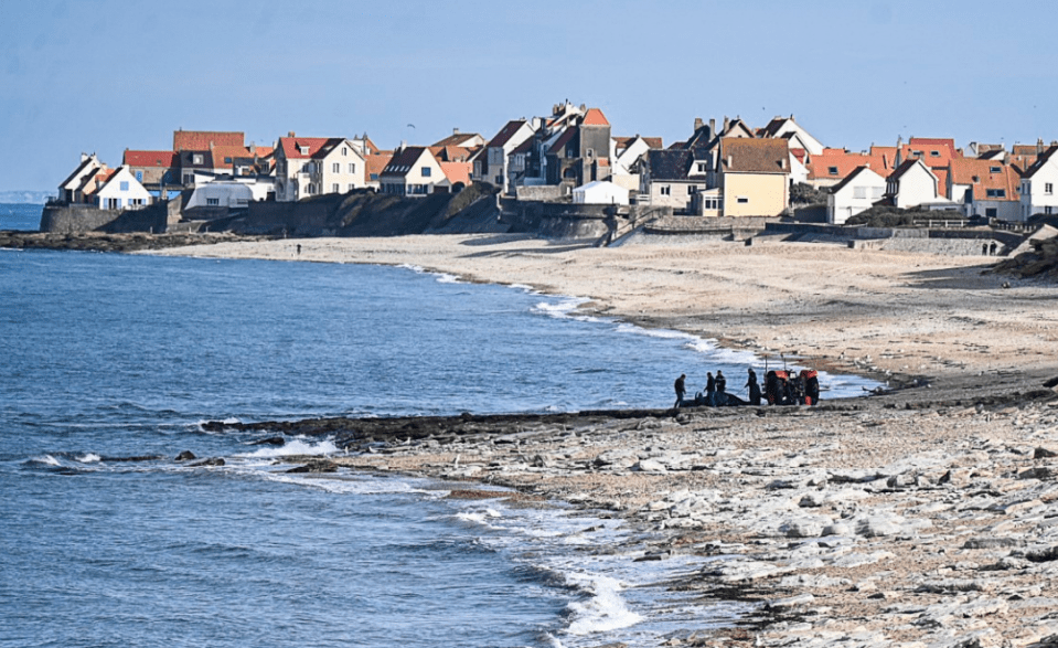 a group of people standing on a rocky beach near the ocean
