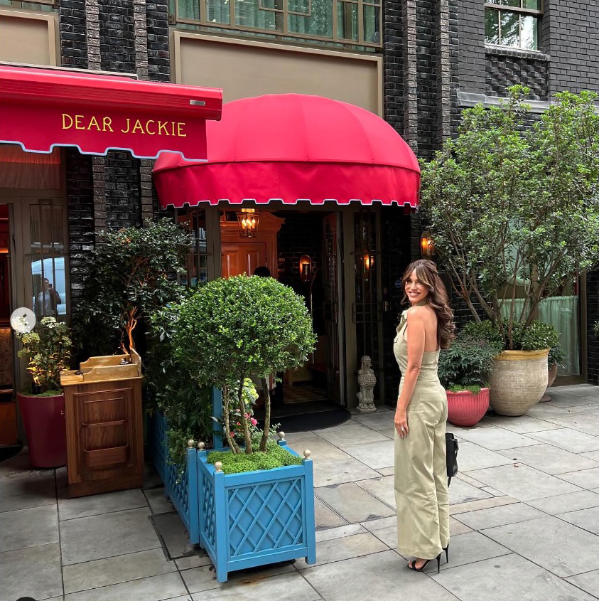 a woman stands in front of the dear jackie restaurant