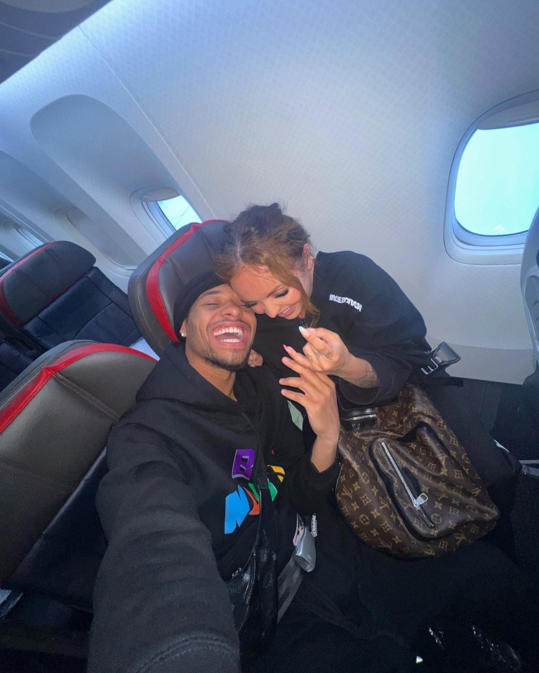 a man and a woman are sitting on an airplane and the woman is wearing a louis vuitton bag