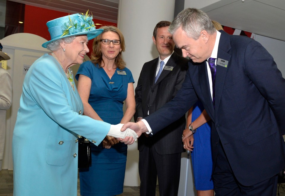 queen elizabeth shakes hands with a man in a suit