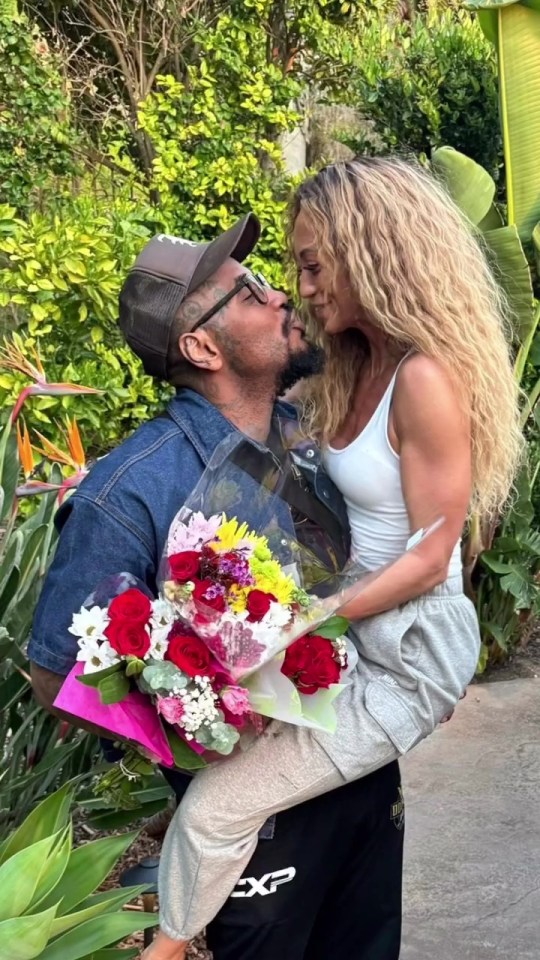 a man is kissing a woman who is holding a bouquet of flowers