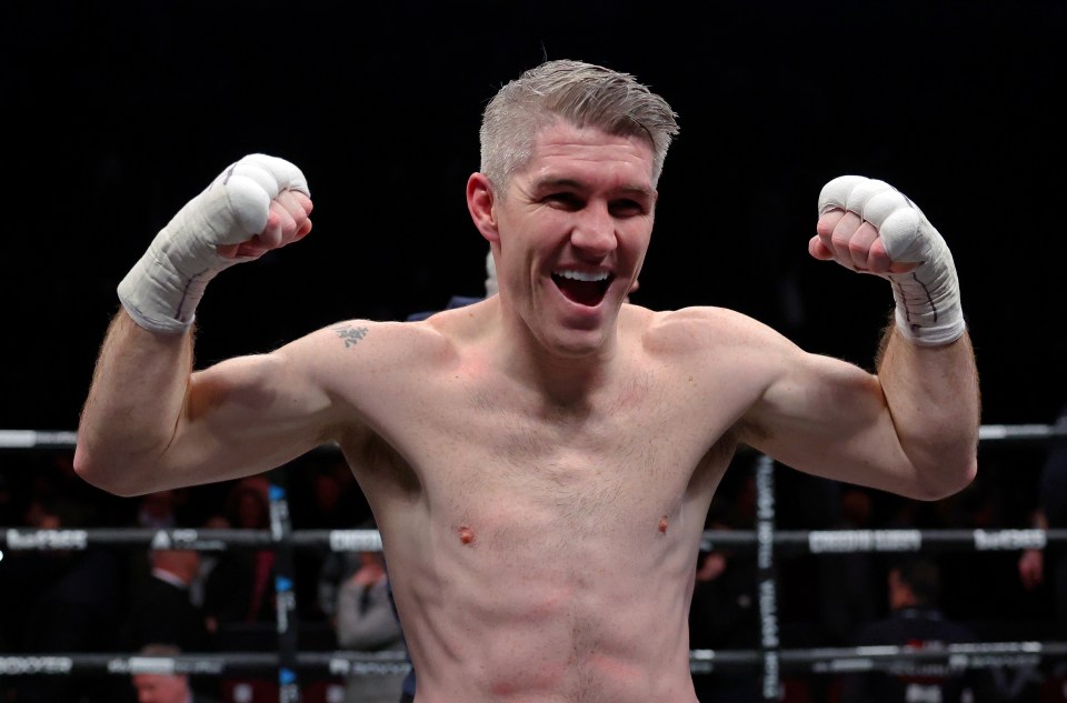 a man in a boxing ring with his arms in the air