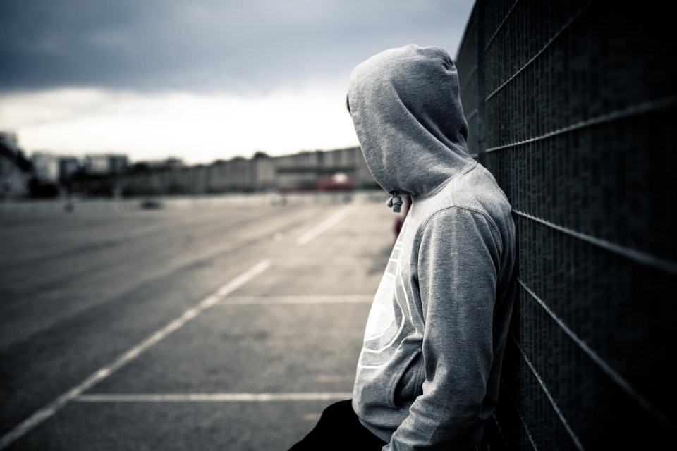 a man leaning against a wall with his head down