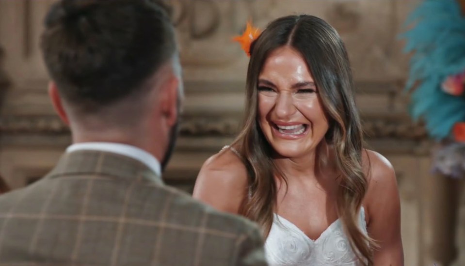 a woman in a wedding dress is crying while looking at a man in a suit