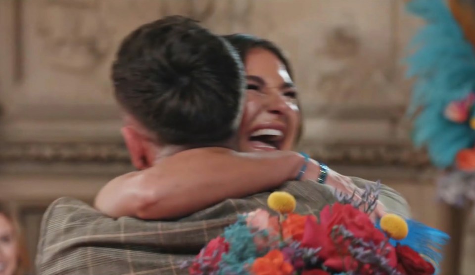 a man is hugging a woman who is holding a bouquet of flowers
