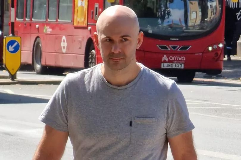 a man stands in front of a red arriva bus