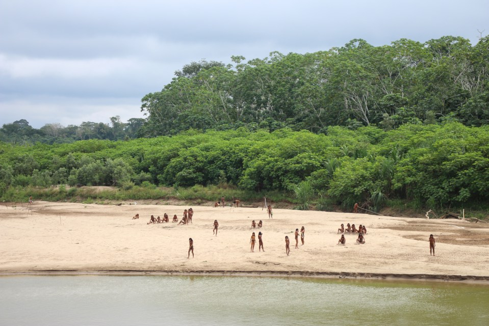 a group of people standing on a sandy beach near a body of water