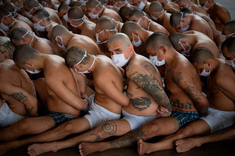 a man with a tattoo on his stomach is surrounded by other men