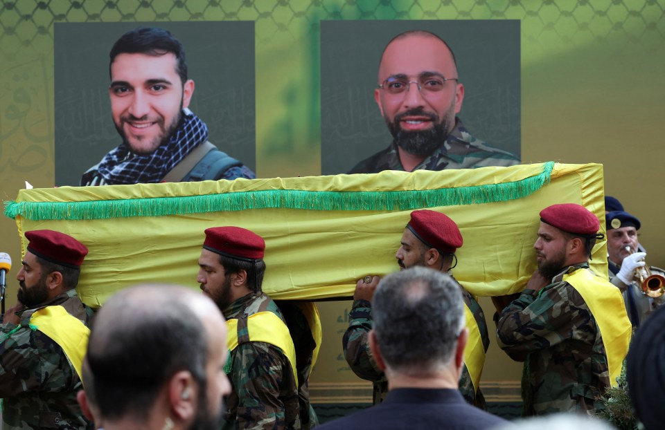 a group of soldiers carrying a yellow coffin with two pictures on it